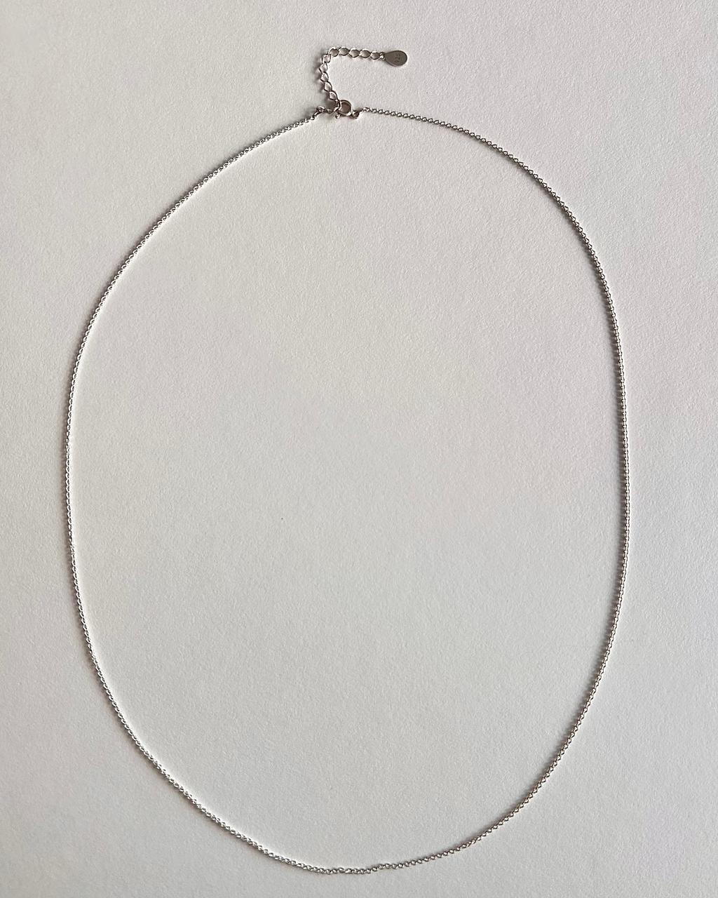 Silver necklace on a light gray background