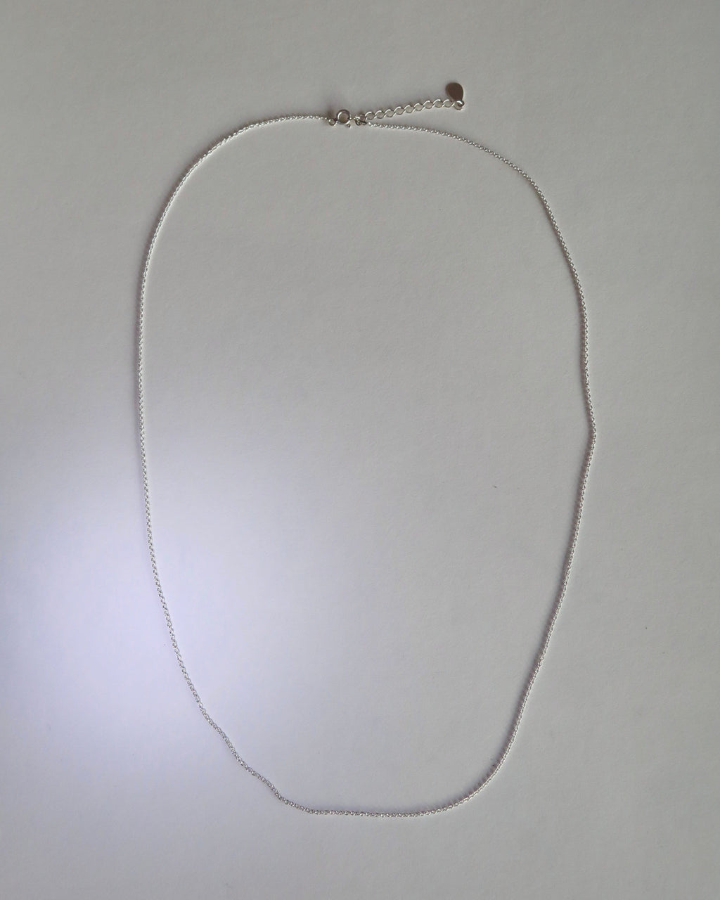 Silver necklace on a light gray background