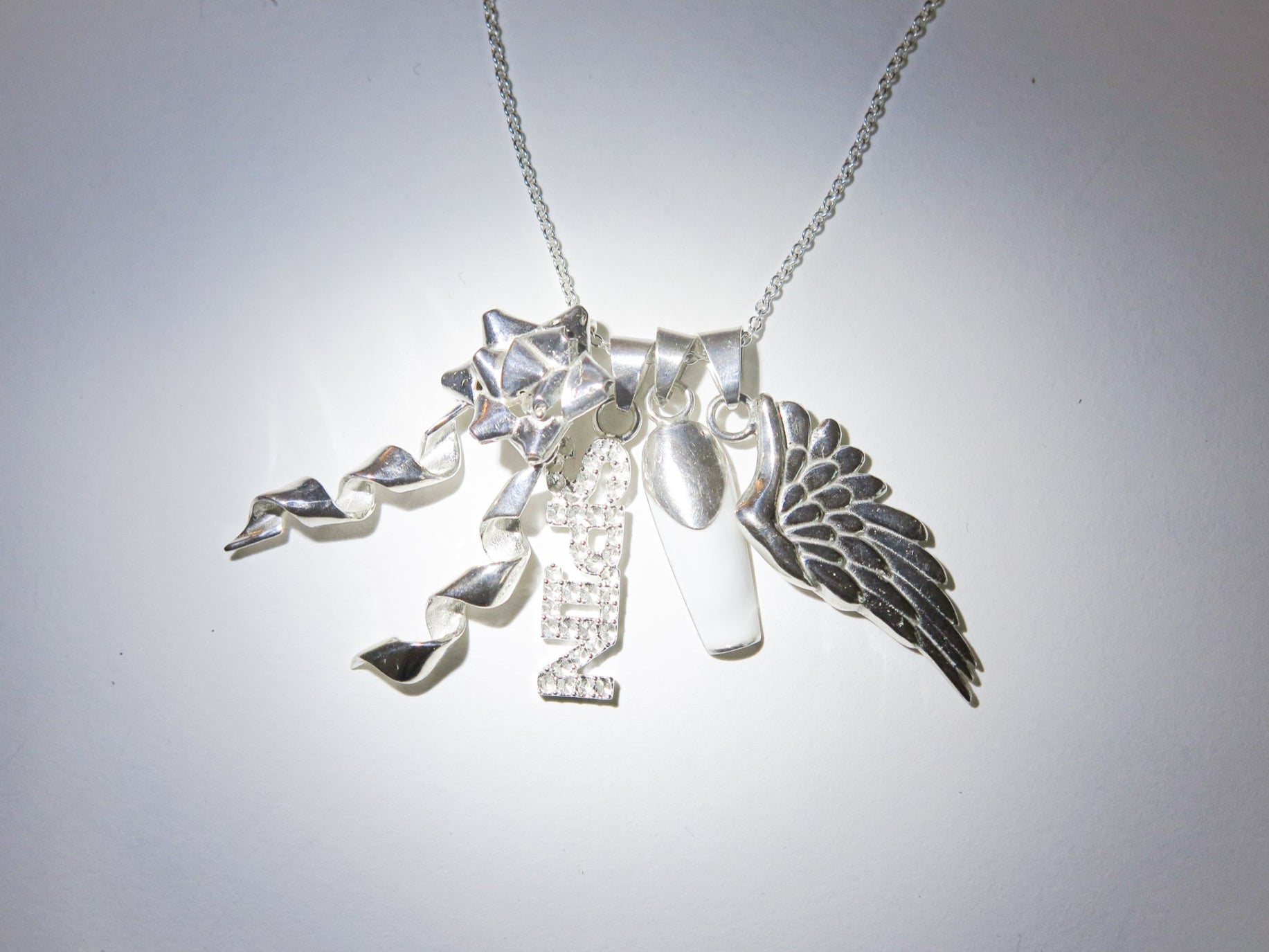 Silver necklace with various charms on a light gray background
